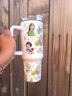 someone is holding up a travel mug with disney characters on it