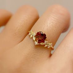 Cue the romance with our stunning Heart’s Desire Red Garnet Ring. This perfect expression of true love features a heart-shaped red garnet center stone along with a curved white topaz leafy band that adds a natural charm. A cherished keepsake that radiates love from every angle. ✦ Available in both 14K yellow gold vermeil (14K yellow gold plated over a sterling silver base) and 10K solid yellow gold. Red Stone Wedding Rings, Heart Shaped Ruby Ring, Garnet Promise Rings, Garnet Heart Ring, Red Rings Engagement, Red And Gold Ring, Gold Red Jewelry, Heart Stone Ring, Red Promise Rings