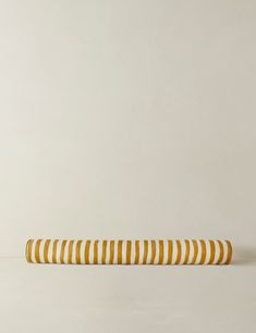 a yellow and white striped object sitting on top of a floor next to a wall