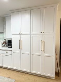 a kitchen with white cabinets and wood floors