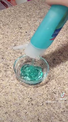 someone is using a toothbrush to brush the green liquid in a glass bowl on a counter