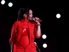 a woman in a red outfit singing into a microphone