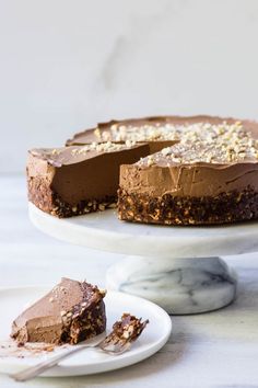 a chocolate cake with one slice missing from it on a white plate next to another piece