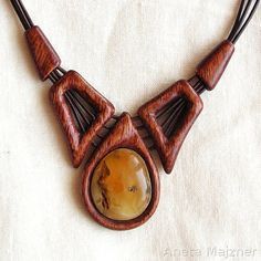 a wooden necklace with an oval stone in the center