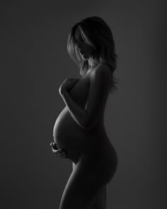 a pregnant woman is posing for a black and white photo with her hands on her hips