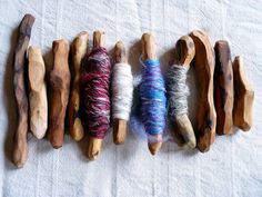 several skeins of yarn are lined up on a tablecloth with wooden pegs