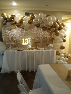 a table topped with white and gold balloons