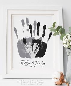 a white frame holding a black and grey hand print with the words family on it