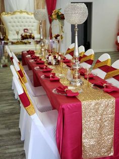 the table is set with red and gold linens, silver candlesticks, and white chairs