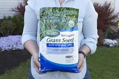 a person holding a bag of grass seed