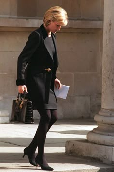 a woman in black is walking down the street