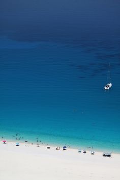 people are on the beach with boats in the water