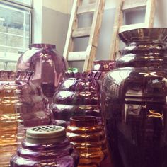 several large vases are lined up on the floor in front of a ladder and window