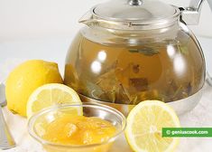 a tea pot filled with lemons on top of a table next to two cups