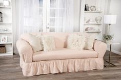 a living room with a pink couch and white bookshelf in the back ground