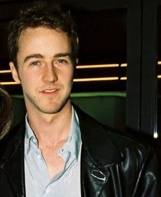 a man in a black leather jacket standing next to a woman wearing a white shirt