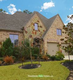 a brick and stone house with trees in the front yard