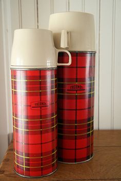 two red and yellow tins sitting on top of a wooden table next to each other