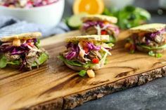 three sandwiches with lettuce, tomatoes and other vegetables on a wooden cutting board