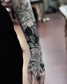 a person with a flower tattoo on their arm holding onto the hand of another person