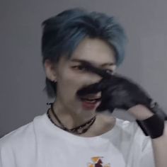 a man with blue hair and black gloves on his face