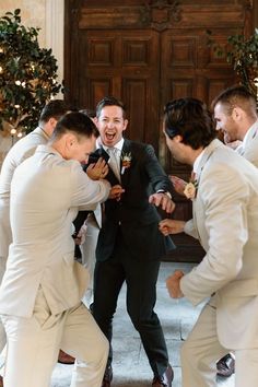 a group of men standing next to each other in front of a door with their arms around one another