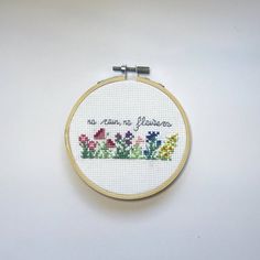 there is a cross stitch pattern in the hoop with words on it that say no rain, no flowers