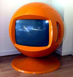 an orange television sitting on top of a wooden floor next to a wall with the caption 22 crt - 33'dida ball