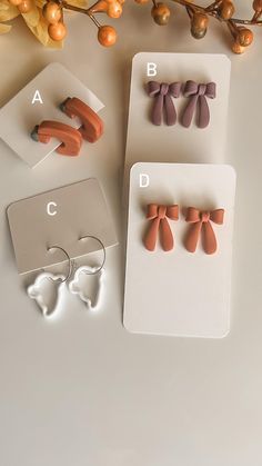 three pairs of ear clips sitting on top of a white surface next to some flowers