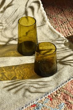 two yellow glass cups sitting on top of a rug