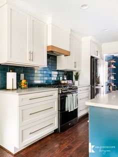 a kitchen with white cabinets and blue backsplash