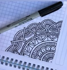 a pen is sitting on top of a notebook with an intricate design in the background