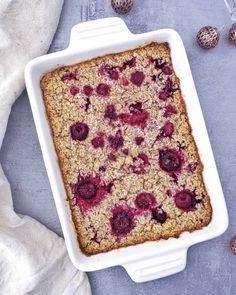 a baked dessert in a white casserole dish with berries on top and eggs around it