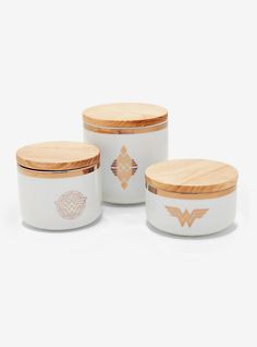 three white canisters with wooden lids and designs