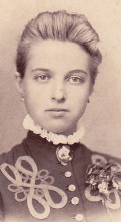 an old black and white photo of a woman wearing a collared shirt with flowers on it