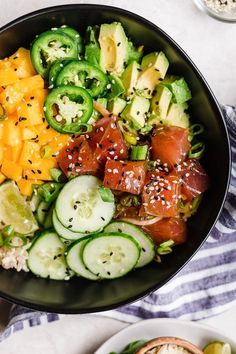 a salad with cucumbers, tomatoes, and other vegetables in a black bowl