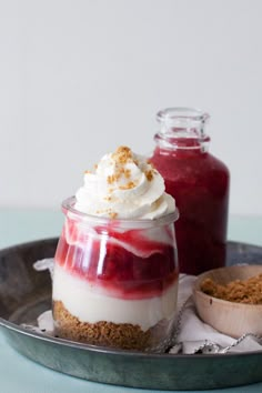 two desserts in small glass containers with whipped cream and cranberry sauce on the side