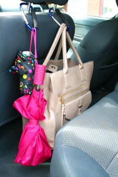 a purse and umbrella in the back seat of a car, with other items hanging from it