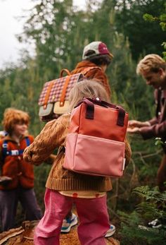 three children with backpacks walking through the woods