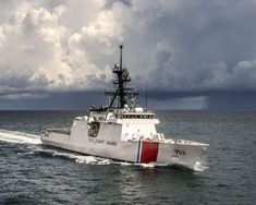 a large white boat in the middle of the ocean on a cloudy day with storm clouds