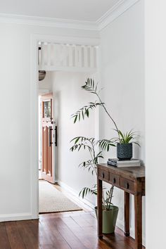 a houseplant sits on a wooden table in the entryway to a home