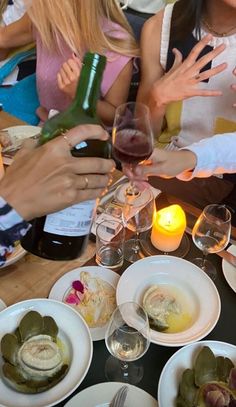 a group of people sitting around a table with food and wine