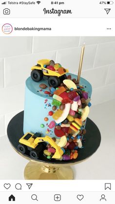 a blue cake with lots of colorful candies on top and a toy truck in the middle