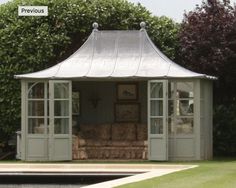 a white gazebo sitting in the middle of a lush green field next to a pool