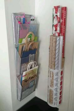 there is a small storage rack on the wall next to some rolls of wrapping paper