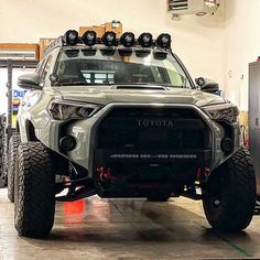 the front end of a toyota truck parked in a garage with its lights on and four wheel drive