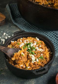 a skillet filled with food on top of a blue cloth next to a wooden spoon