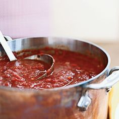 a large pot filled with red sauce on top of a wooden table