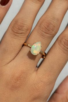 a woman's hand with a gold ring and an opal stone on it