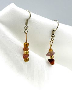 From Kaleigh's Collection:    Lightweight earrings dangle with chips of Carnelian gemstone and glass beads. Pretty iridescent tube shape small beads of glass combined with the golden orange hues of Carnelian chips make these earrings a delightful reminder of autumns colors. With a dangle length of 1-1/2 inch these pretty earrings will add a touch of amber glow to your day. One of a kind made with care. Bead Earring, Golden Amber, Orange Hues, Small Beads, Earring Gift, Lightweight Earrings, Amber Color, Pretty Earrings, Light Weight Earrings